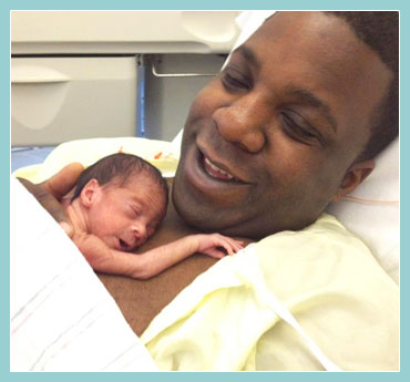 Smiling father with premature child resting on his chest.
