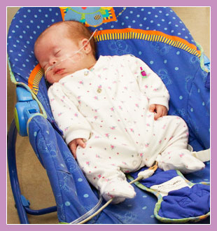 Photo of a premature child asleep in a baby seat.